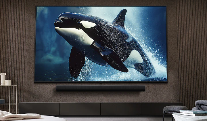 Телевизор LG TV с впечатляюще большим экраном, установленный на стене над звуковой панелью LG Soundbar в гостиной в современном стиле.