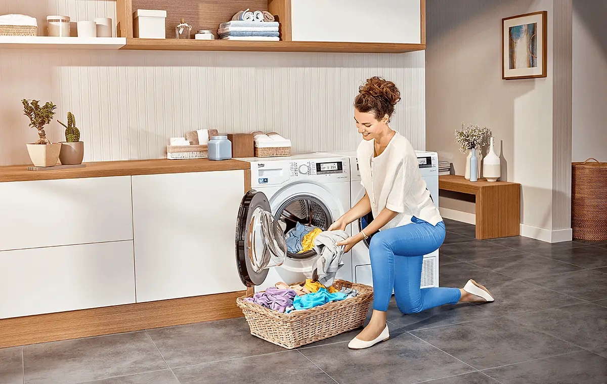 Beko WSRE6H612ZAWI фронтальная загрузка &mdash; женщина загружает бельё в барабан